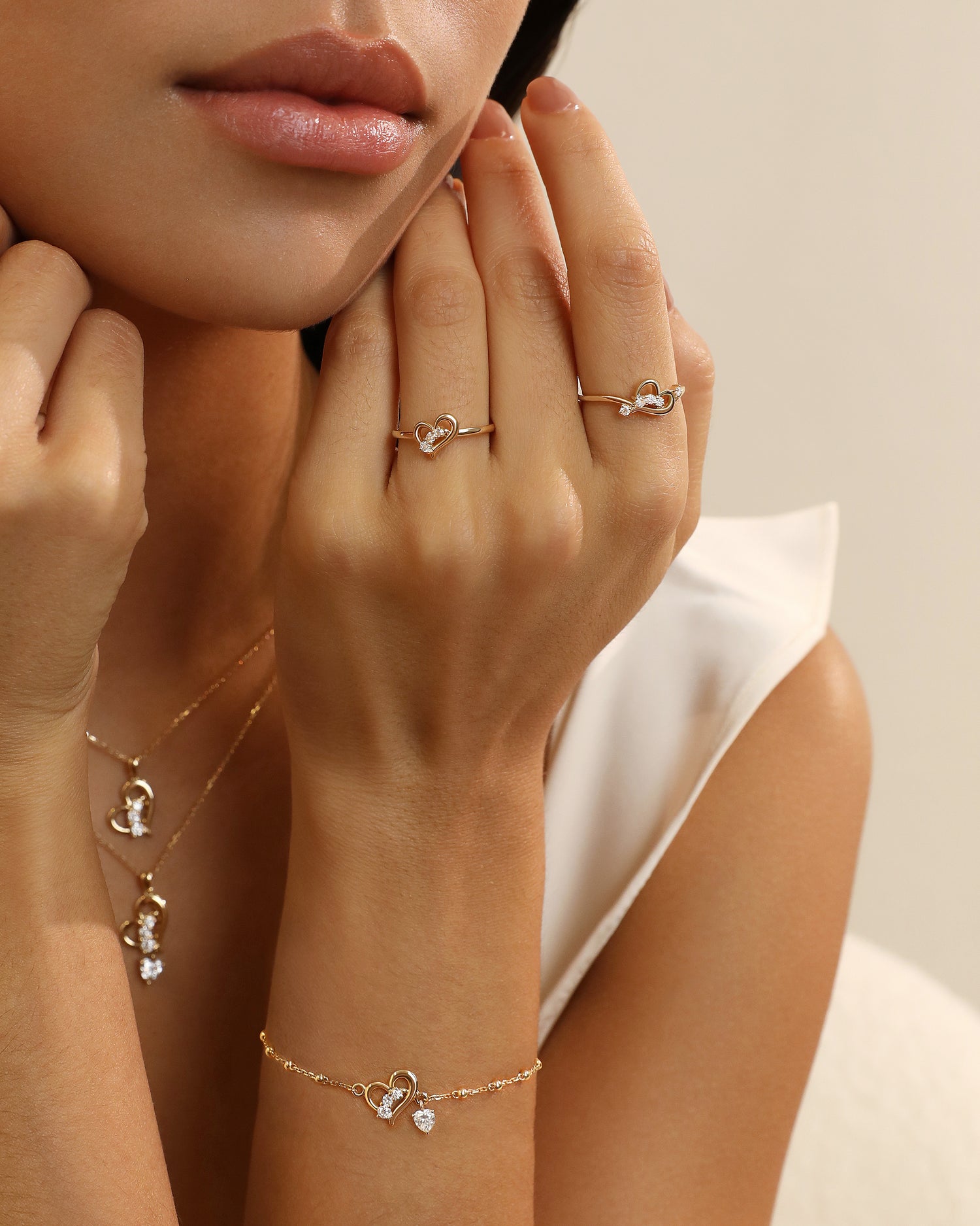 Close-up of a hand wearing gold rings and a bracelet with small heart charms.