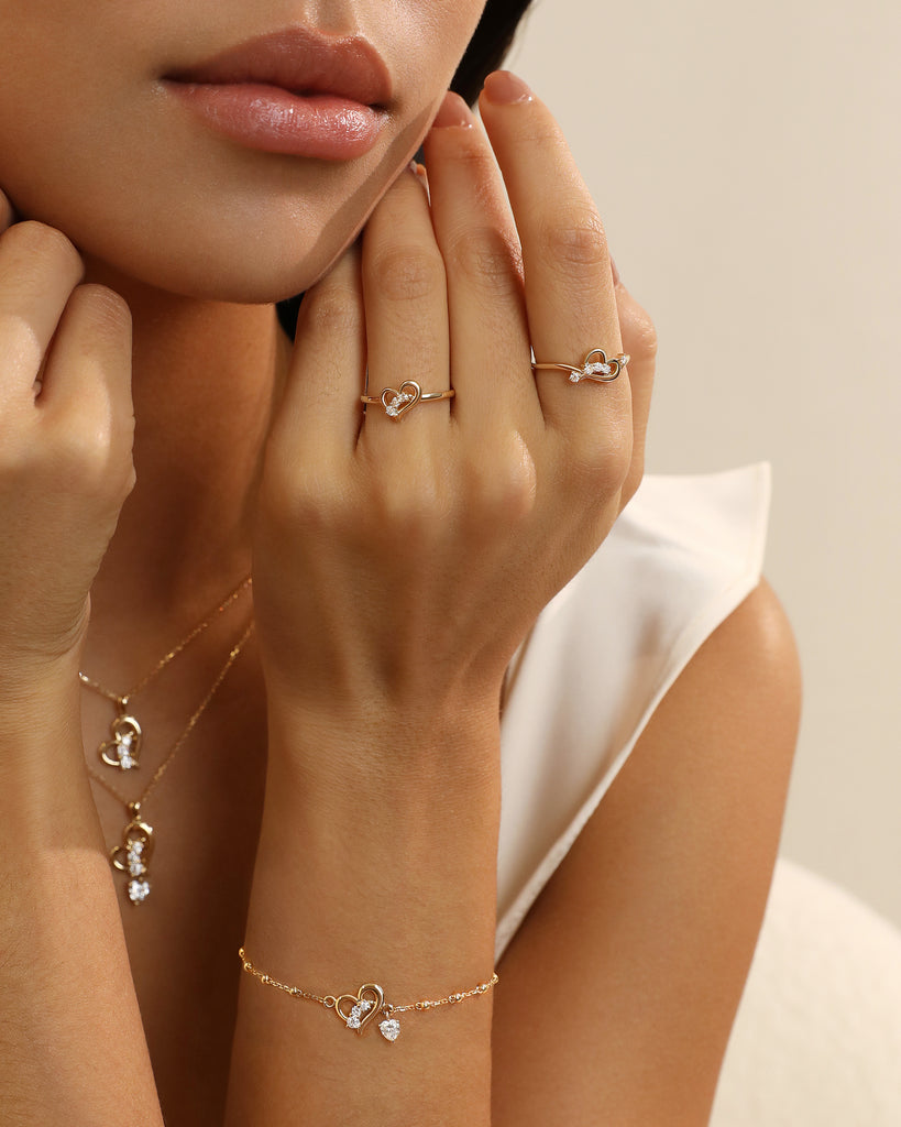 Close-up of a hand wearing gold rings and a bracelet with small heart charms.
