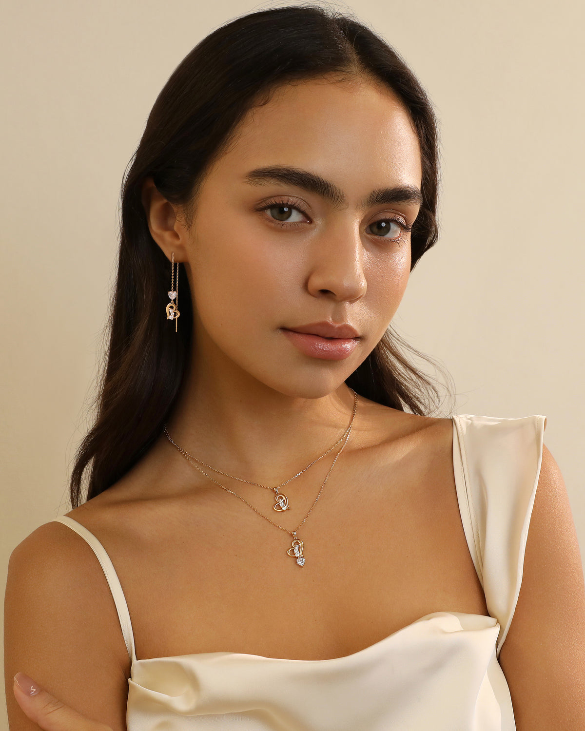 Model styling layered Meissa Heart of Freedom Necklaces in solid gold with matching heart jewelry.
