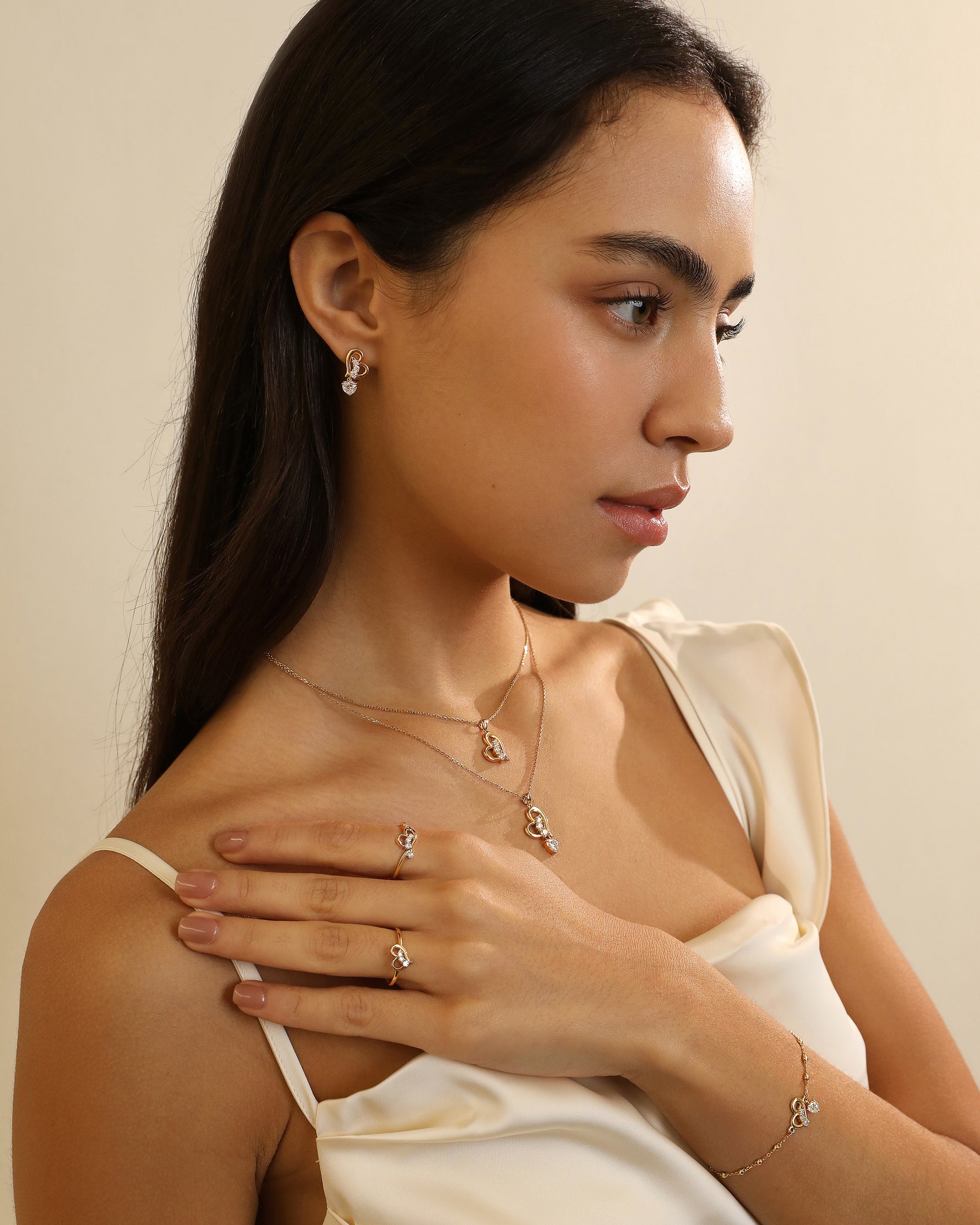 Close-up of model wearing layered Meissa Heart of Freedom Necklaces in solid gold with coordinating heart rings and bracelet.