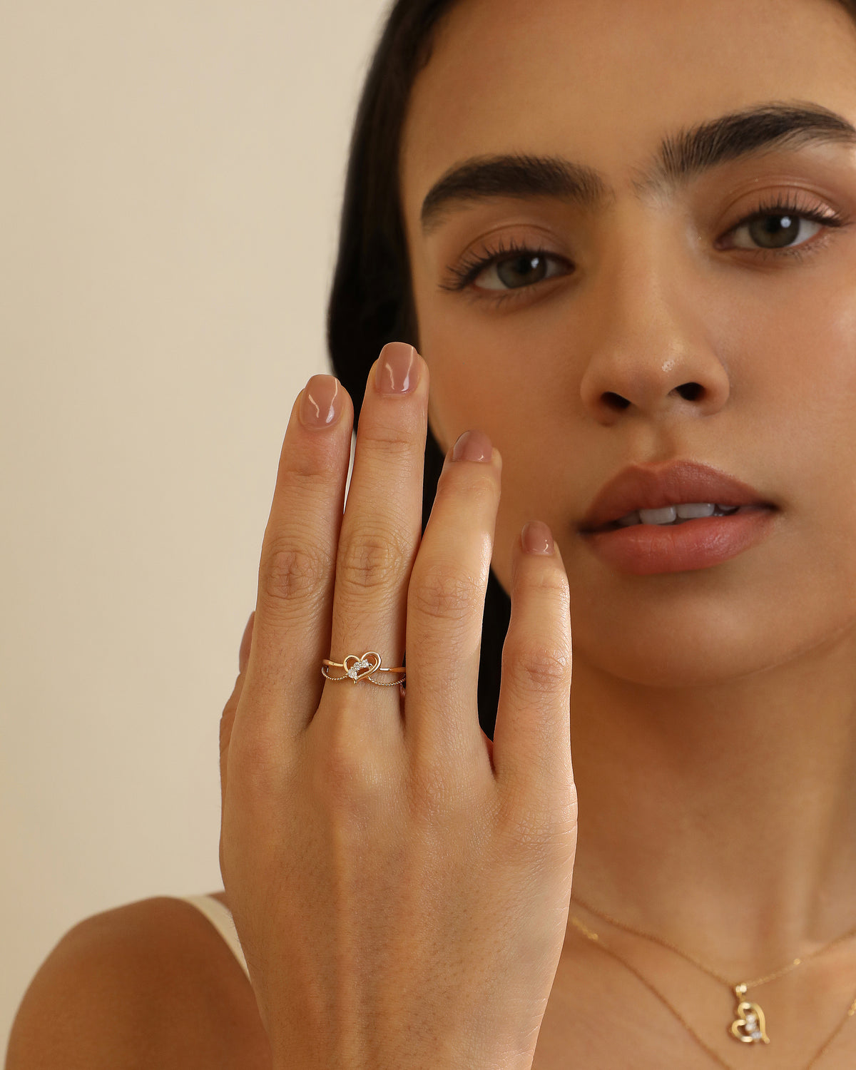 Model wearing Luminous Heart Ring in solid gold with a delicate heart and moissanite design.