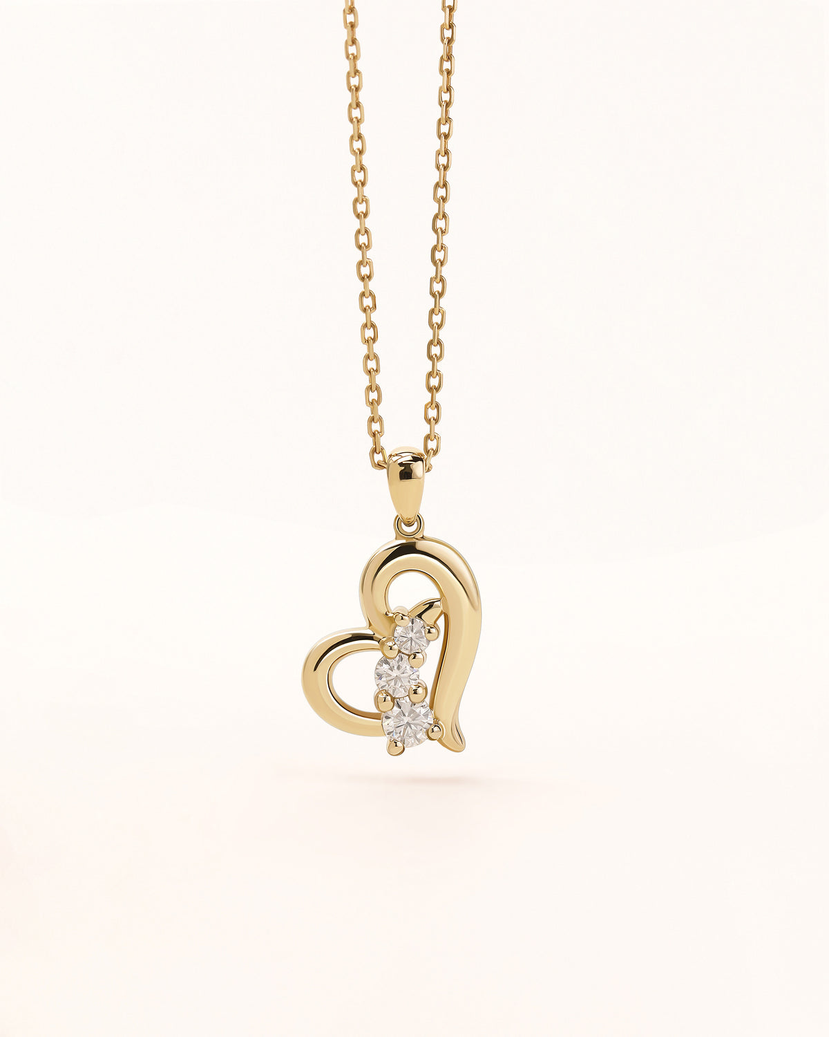 Close-up of Meissa Heart of Freedom Necklace in solid gold with an open heart pendant and three sparkling moissanite stones.