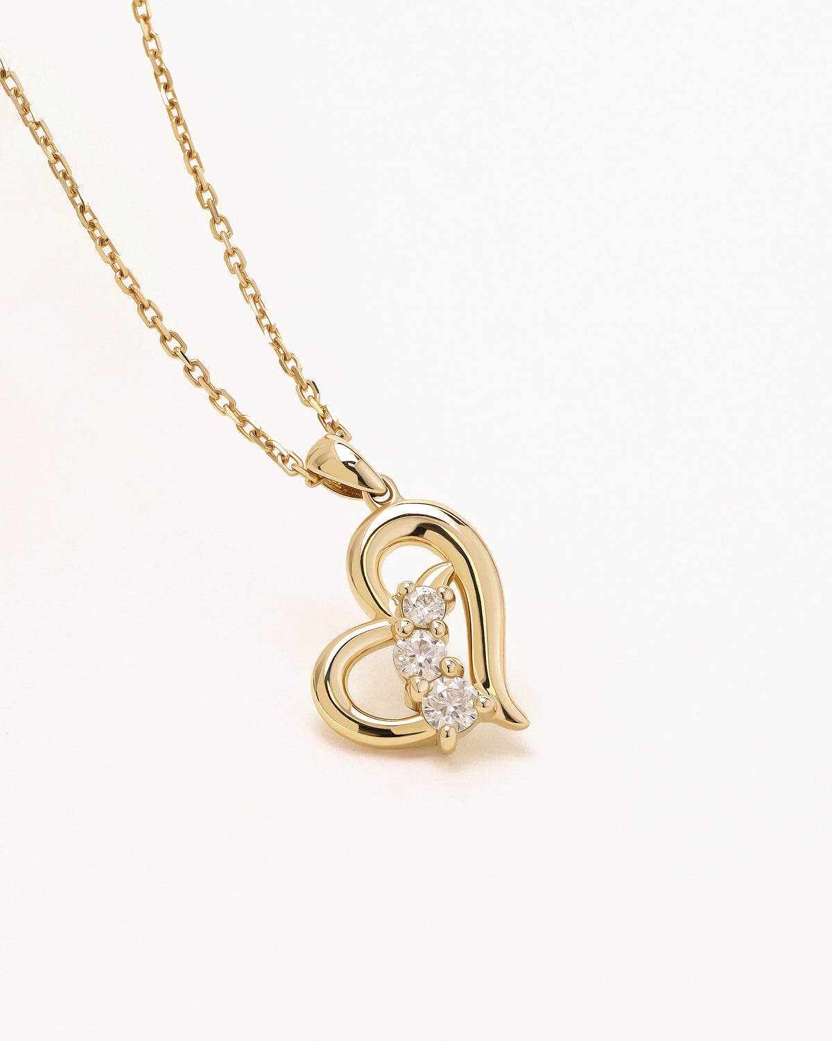 Close-up of Meissa Heart of Freedom Necklace in solid gold with an open heart pendant and three sparkling moissanite stones.