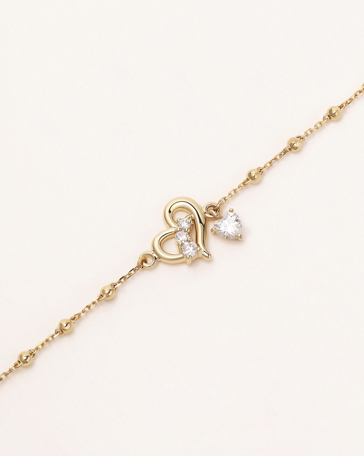 Close-up of Heart of Freedom Bracelet in solid gold with heart motif and heart-shaped moissanite drop.