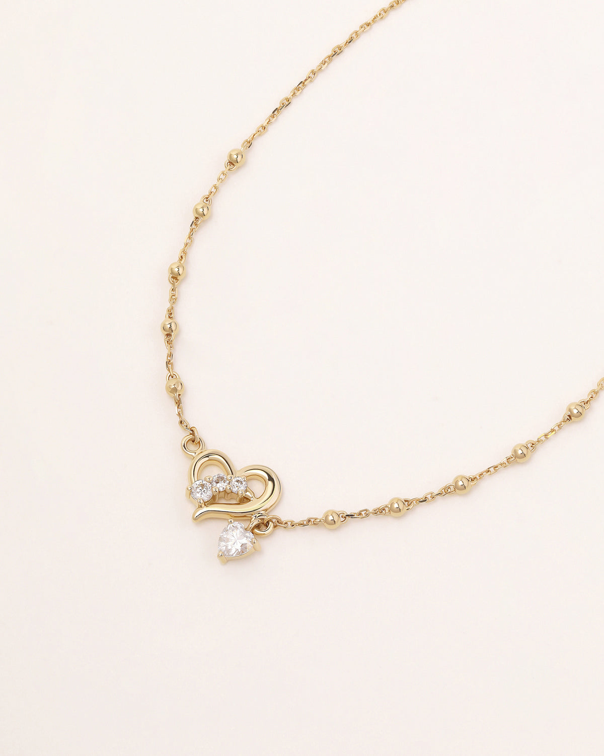 Front view of Heart of Freedom Bracelet in solid gold with open heart design, moissanite accents and beaded chain.