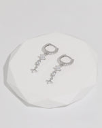 Starlight Drop Huggie Earrings displayed as a pair on a white faceted tray, highlighting the delicate drop design and sparkling details.