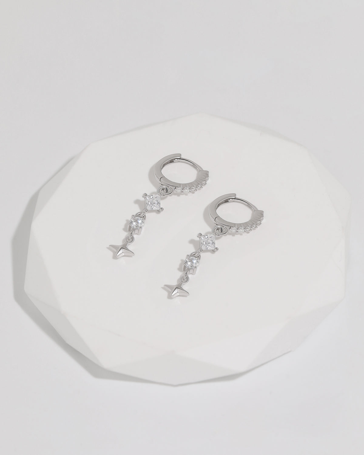Starlight Drop Huggie Earrings displayed as a pair on a white faceted tray, highlighting the delicate drop design and sparkling details.