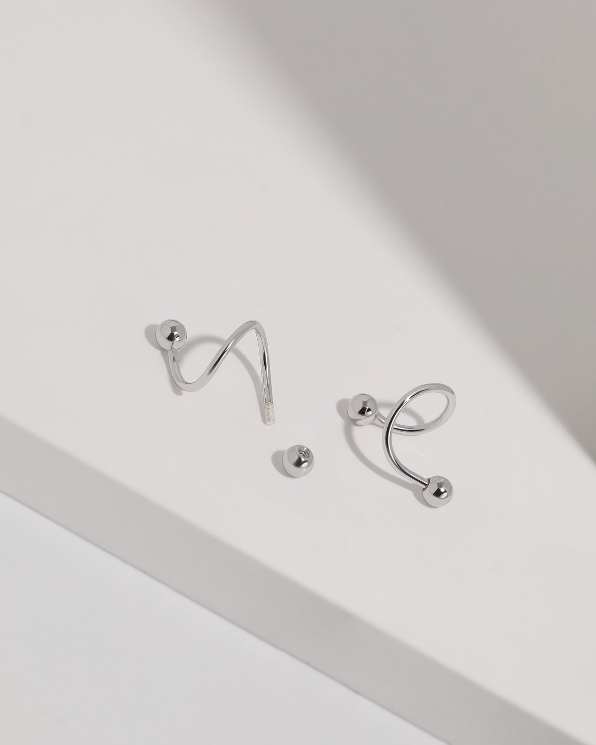 Ball Spiral Screw Back Earrings in silver color shown with one screw back ball removed to display the threaded post and fastening design.