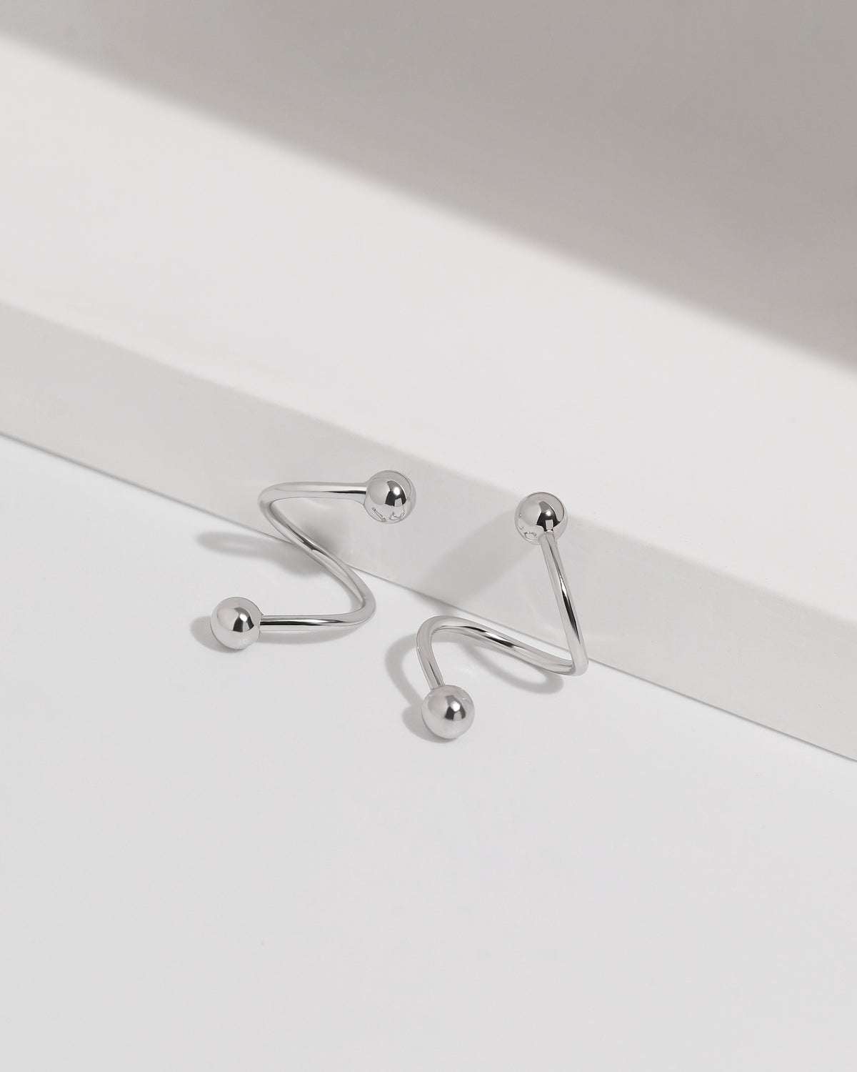 Ball Spiral Screw Back Earrings arranged on a white display with polished ball ends and a smooth curved design.