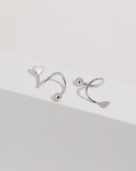 Heart Spiral Screw Back Earrings in 925 sterling silver displayed on a white surface, showing the heart-shaped ends, sculptural spiral curves, and polished ball details.