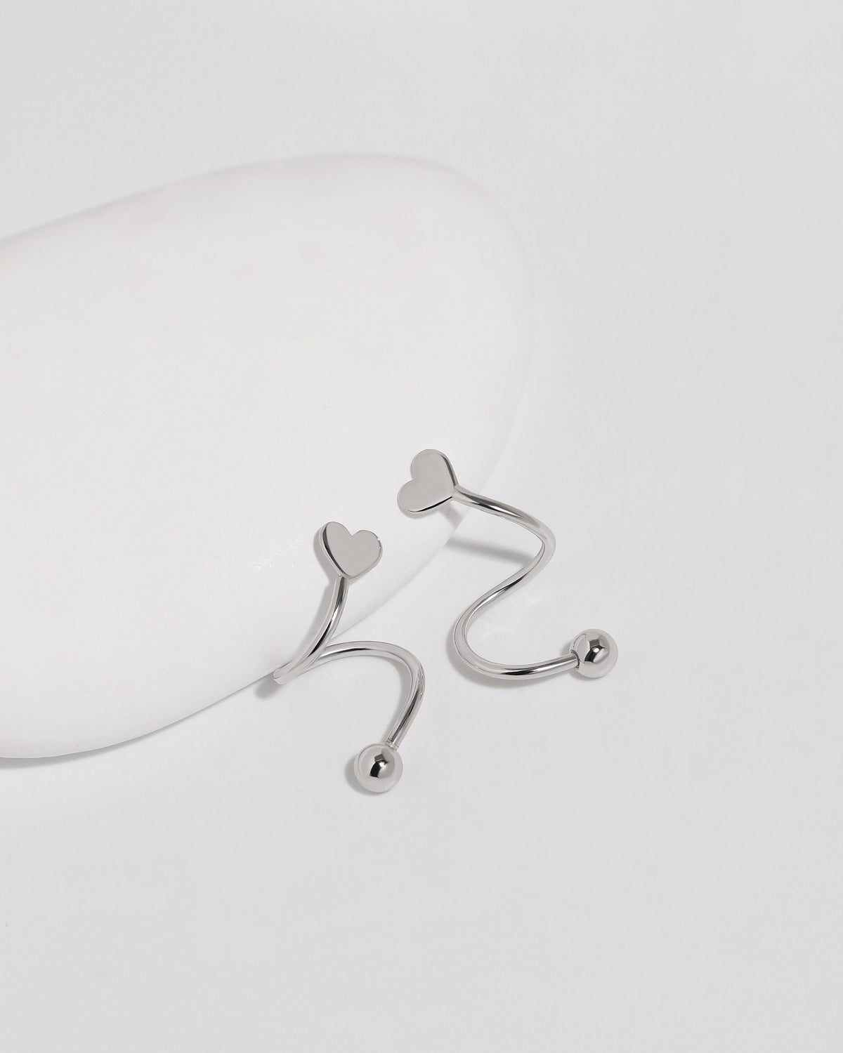 Heart Spiral Screw Back Earrings in silver color displayed from multiple angles, highlighting the smooth spiral curves, polished heart ends, and round screw back balls.