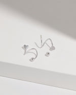 Heart Spiral Screw Back Earrings in silver color displayed on a white surface, highlighting the smooth curved construction, heart-shaped ends, and round screw back balls.