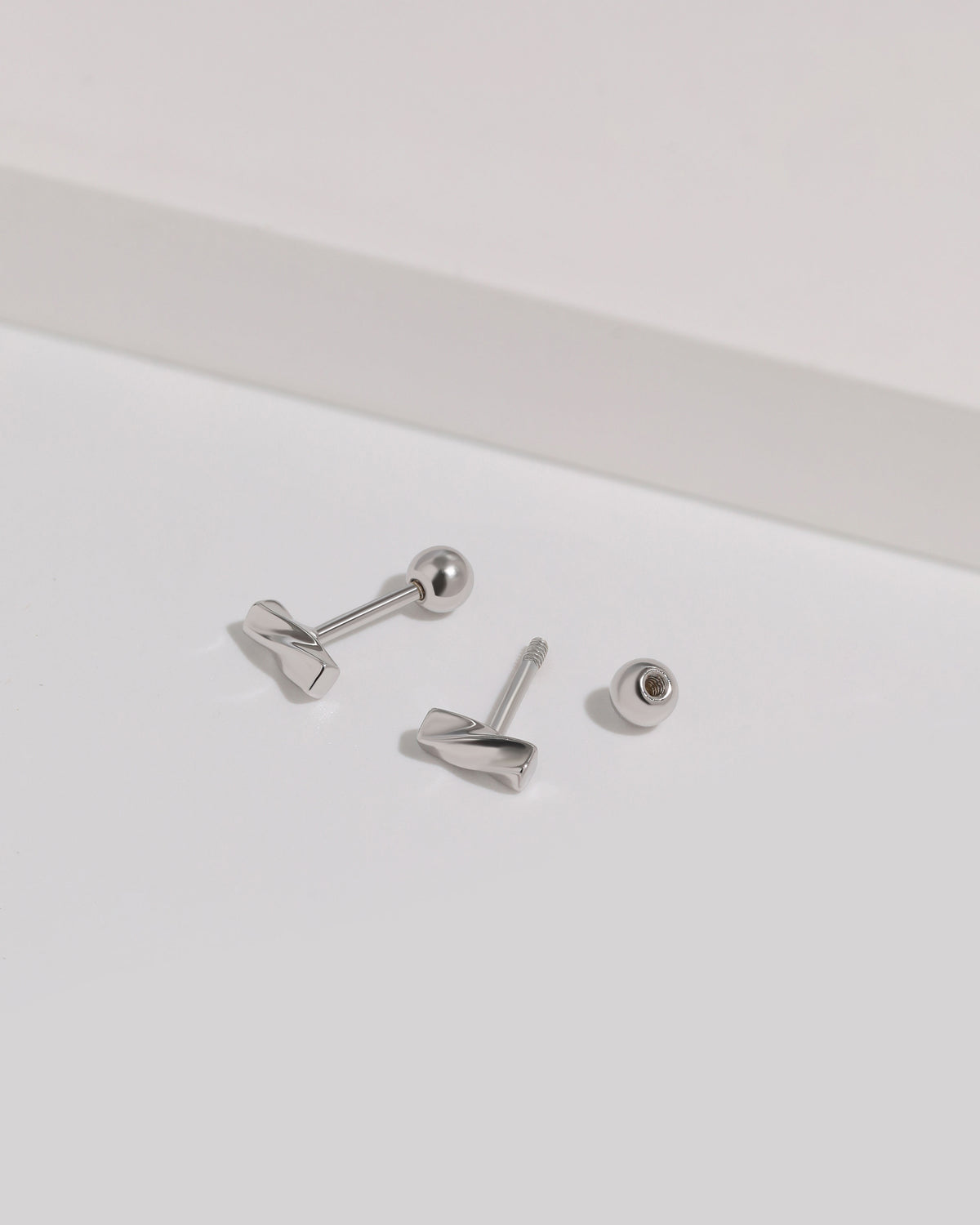 Twist Bar Screw Back Earrings shown with one round screw back removed, revealing the threaded post and screw closure construction.