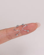 Ball Spiral Screw Back Earrings in silver color displayed on a finger for a close-up view of the curved spiral silhouette and petite size.