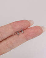Pair of Twist Bar Screw Back Earrings resting on fingertips, showing the petite polished twist bar design and scale.