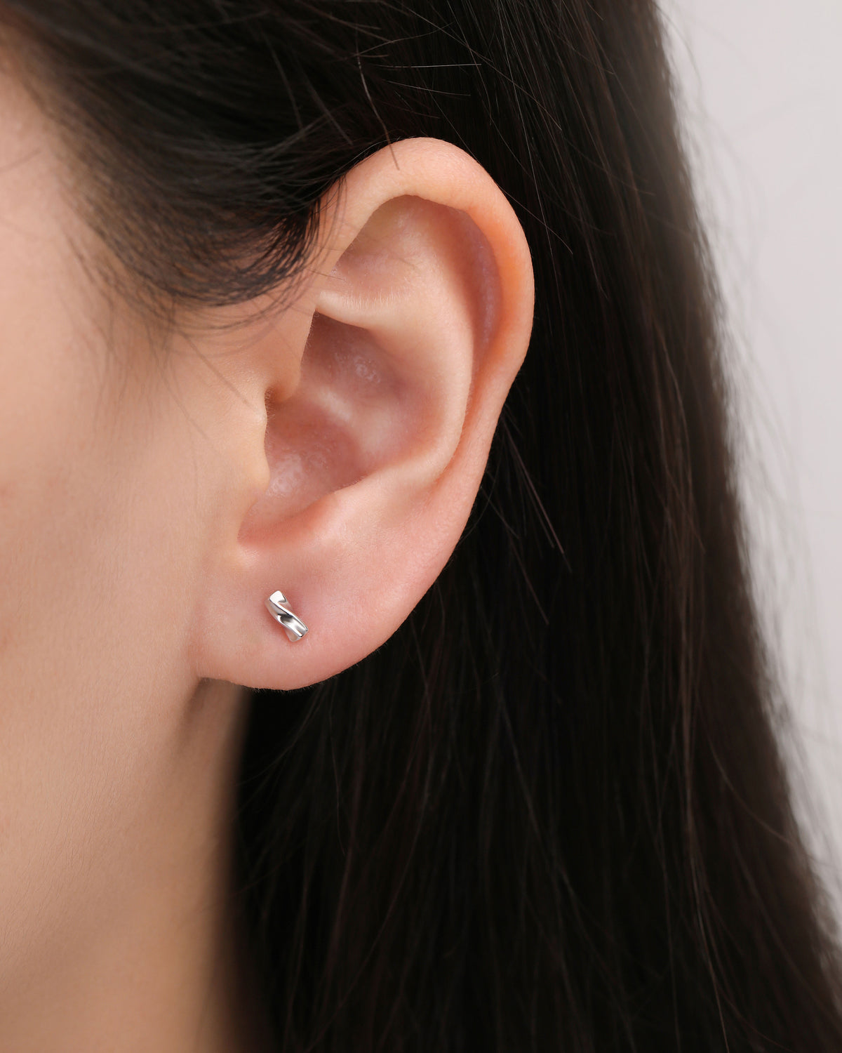 Twist Bar Screw Back Earring worn on the earlobe, showing the minimalist polished silver bar and subtle twisted shape.