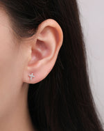 Multiple silver Cross Sparkle Screw Back Earrings resting on fingers to show the petite cubic zirconia cross design and scale.