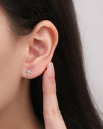 Cross Sparkle Screw Back Earring worn on the earlobe, featuring a petite silver cross design accented with sparkling cubic zirconia.