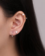 Heart Spiral Screw Back Earrings in silver color shown worn on the earlobe and upper ear, highlighting the curved spiral design with polished heart details and round ball ends.
