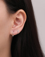Heart Spiral Screw Back Earring in silver color worn on the earlobe, showing how the curved spiral wraps around the ear with a polished heart and round ball end.