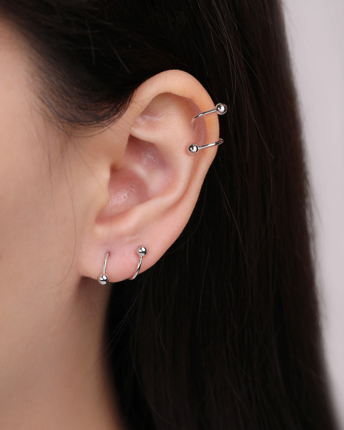 Ball Spiral Screw Back Earrings in silver color worn on multiple ear piercings, showing the curved spiral shape and polished ball details.