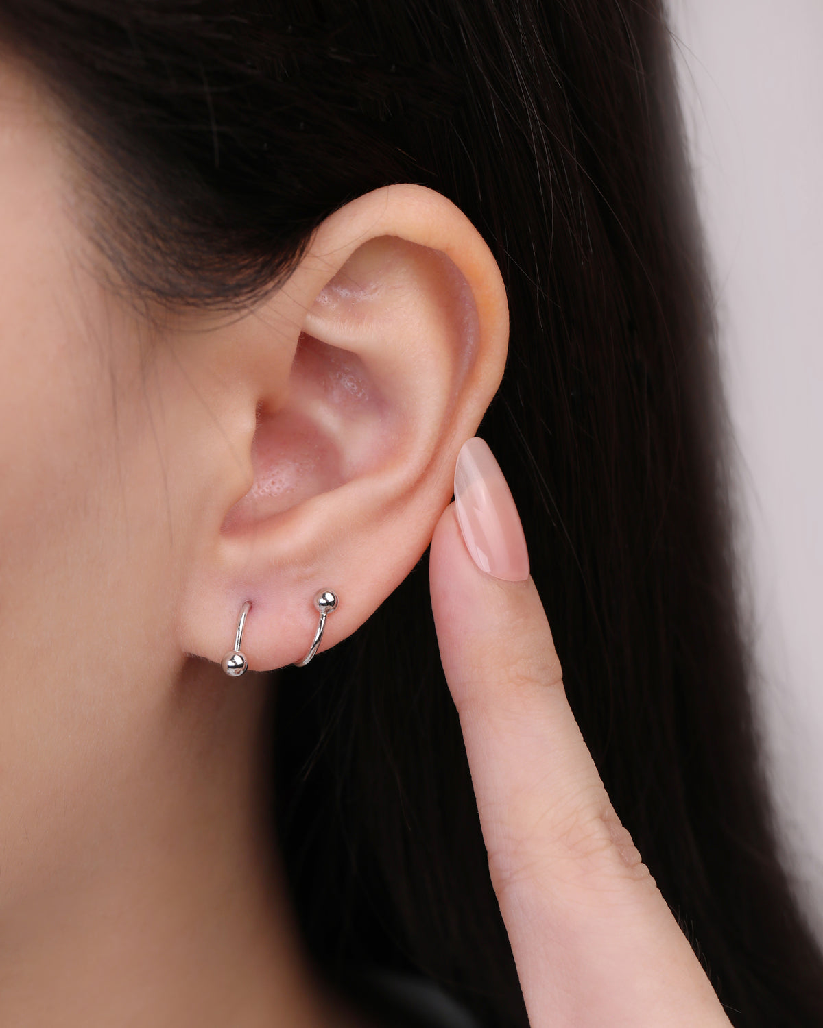 Ball Spiral Screw Back Earring in silver color worn on the ear, showing how the curved spiral design wraps around the earlobe.