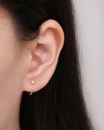 Star Arc Huggie Hoop Earring in gold color worn on the earlobe, featuring a polished five-point star and curved open hoop design.