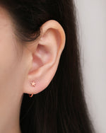 Star Arc Huggie Hoop Earring in rose gold color worn on the earlobe, featuring a polished star and curved open hoop design.