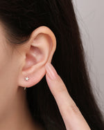 Star Arc Huggie Hoop Earring in gold color shown close up on the ear, highlighting the polished star and open arc hoop shape.