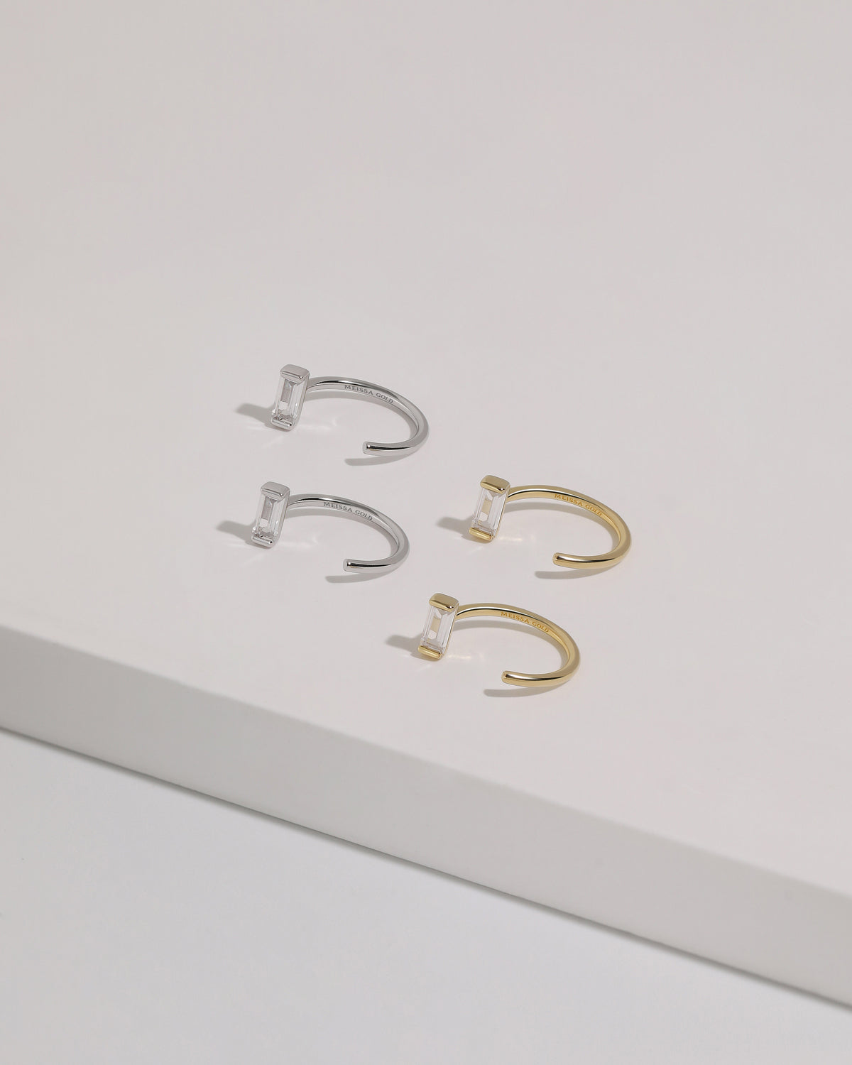 Meissa Baguette Sparkle Huggie Hoop Earrings in silver-tone and gold-tone colors displayed on a white surface.