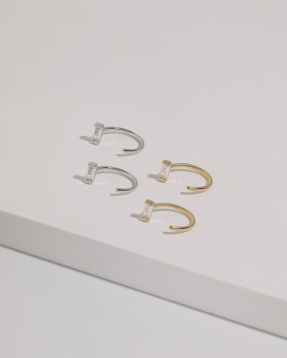 Meissa Baguette Sparkle Huggie Hoop Earrings in silver-tone and gold-tone colors displayed on a white surface.
