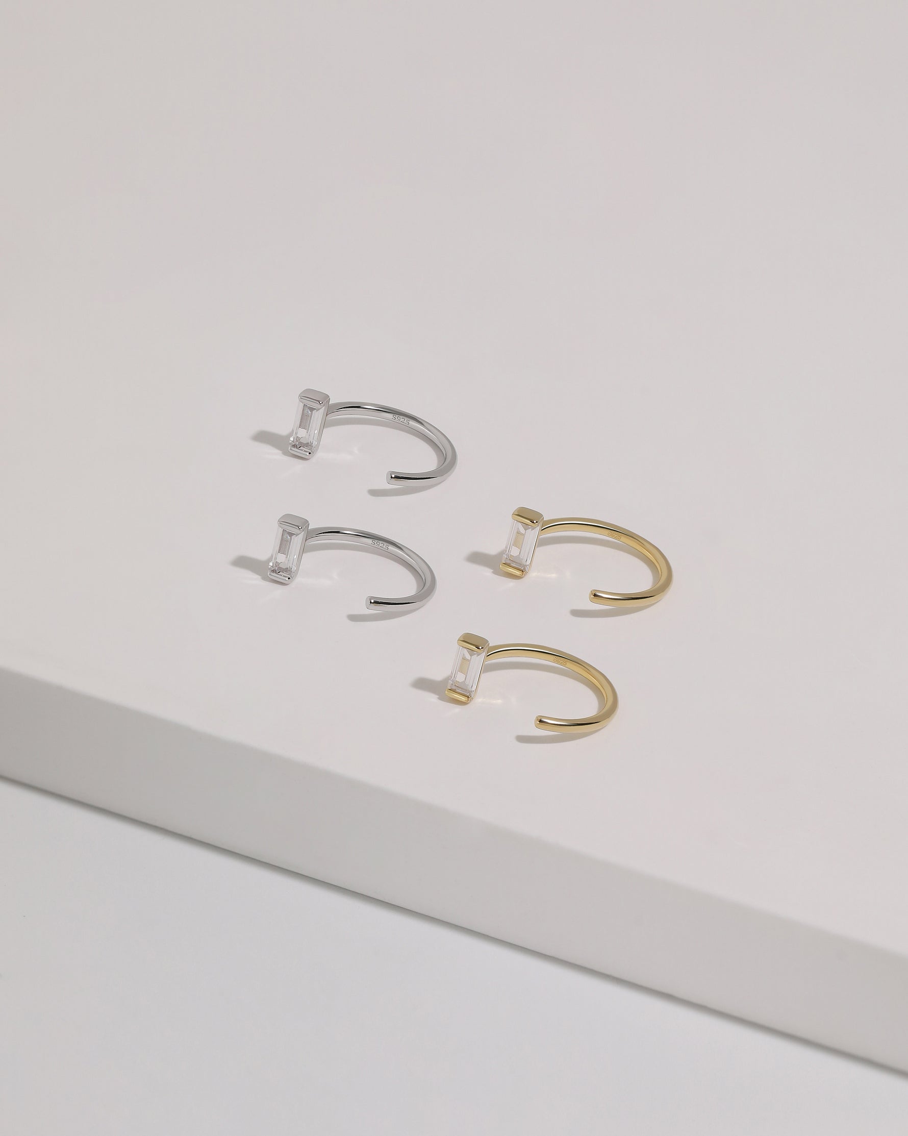 Meissa Baguette Sparkle Huggie Hoop Earrings in silver-tone and gold-tone colors displayed on a white surface.