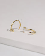 Pair of gold-tone Meissa Baguette Sparkle Huggie Hoop Earrings with clear baguette-cut stones shown from different angles.