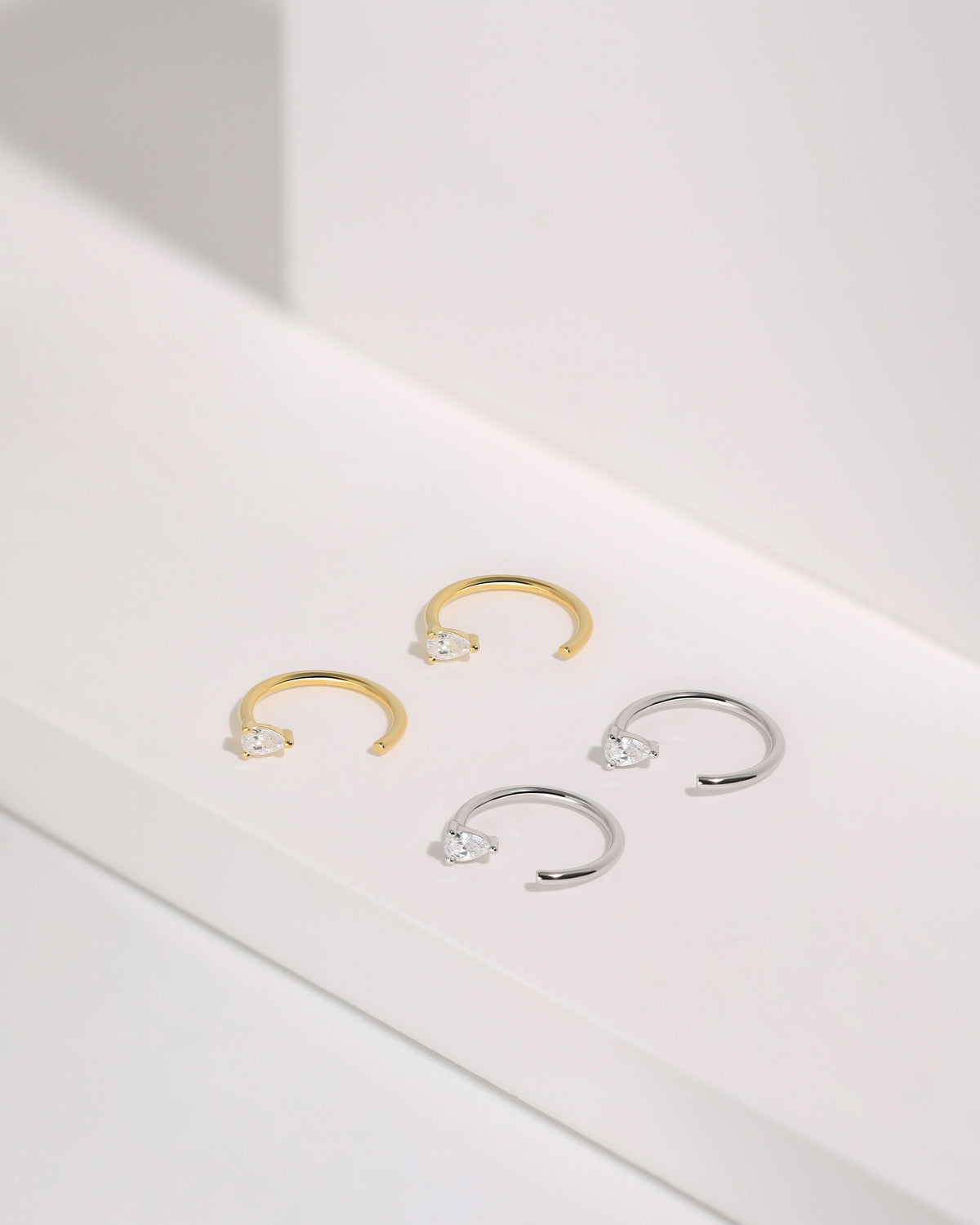 Meissa Pear Sparkle Huggie Hoop Earrings in silver-tone and gold-tone colors displayed on a white surface.
