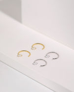 Meissa Pear Sparkle Huggie Hoop Earrings in silver-tone and gold-tone colors displayed on a white surface.