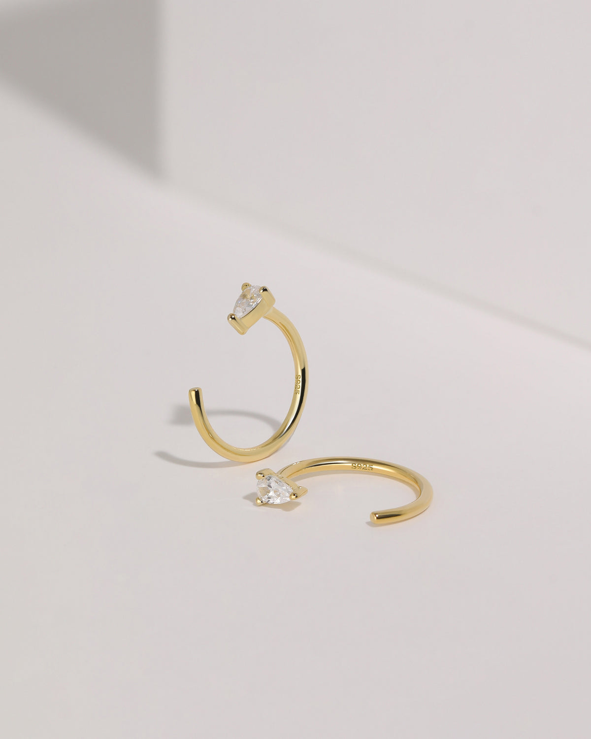 Meissa gold-tone pear-cut clear stone open hoop earrings shown from front and side views.