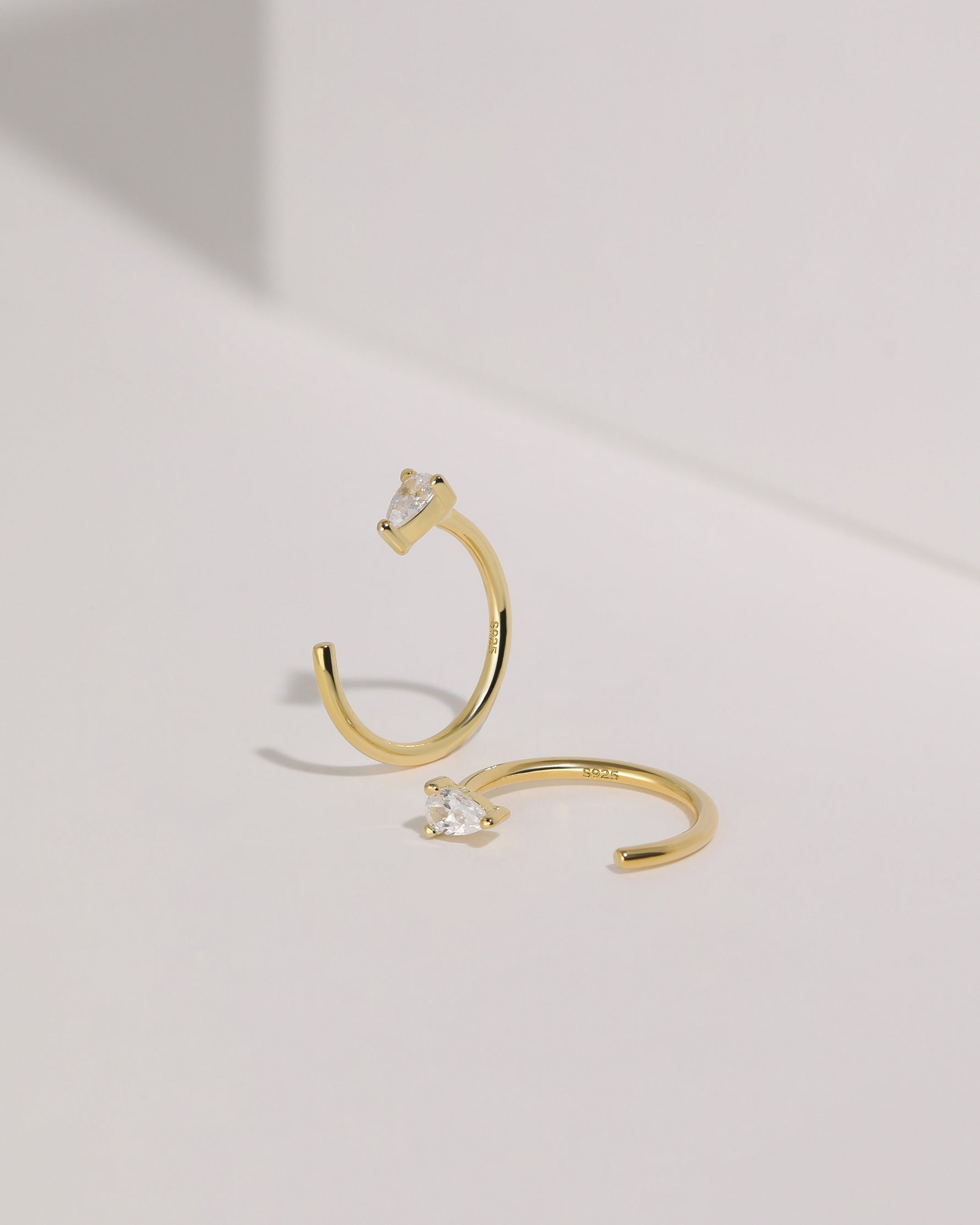 Meissa gold-tone pear-cut clear stone open hoop earrings shown from front and side views.
