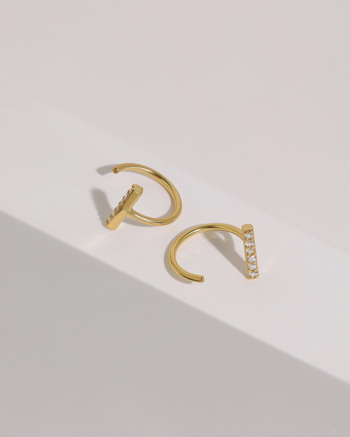 Pair of gold-tone Meissa Sparkling Bar Huggie Hoop Earrings with clear stones shown from front and side angles.