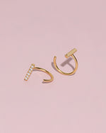 Gold-tone Meissa Sparkling Bar Huggie Hoop Earrings with clear stones shown from front and back angles on a soft pink background.