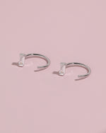 Meissa Baguette Sparkle Huggie Hoop Earrings on a soft pink background.