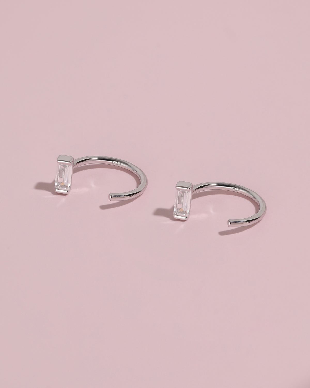 Meissa Baguette Sparkle Huggie Hoop Earrings on a soft pink background.