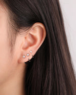 Model wearing silver-tone Meissa Pear Sparkle Huggie Hoop Earring with star huggie hoop earring and round sparkle huggie hoop earring in a stacked ear look.