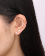 Model wearing a silver-tone Meissa Baguette Sparkle Huggie Hoop Earring and a round sparkle huggie hoop earring in a minimalist stacked ear look.