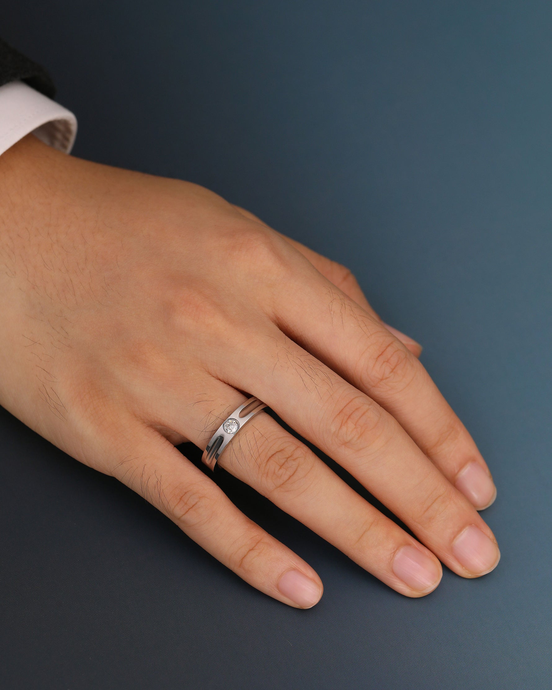 Silver Nova Track Ring in stainless steel worn on a man's finger, showing the round cubic zirconia center stone and polished groove design.