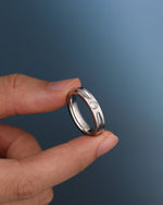 Silver Nova Track Ring in stainless steel held between fingers, showing the polished band, groove details, and round cubic zirconia center stone.