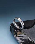Silver Nova Track Ring in stainless steel displayed on black stone with a blue background, showing the polished band and cubic zirconia center stone.