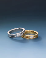 Gold and silver Nova Track Rings in stainless steel displayed together with round cubic zirconia center stones and polished groove details.