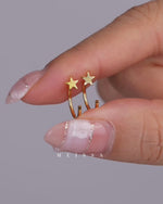 Star Arc Huggie Hoop Earrings in gold color shown in a video featuring the pair held between fingers, a close-up of the curved open hoop construction, and a single earring worn on the earlobe, highlighting the polished five-point star detail and lightweight 925 sterling silver design.