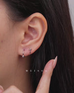 Ball Spiral Screw Back Earrings shown worn on the earlobe, with close-up views demonstrating the curved spiral design, polished ball ends, and screw-back fastening as the earring is removed from the piercing.