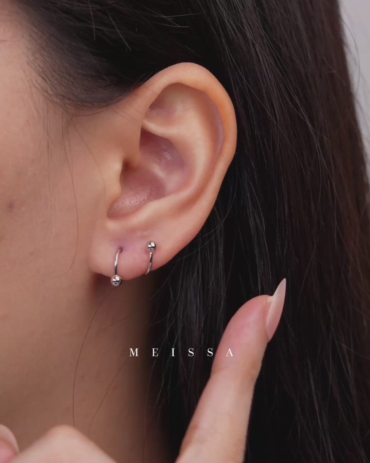 Ball Spiral Screw Back Earrings shown worn on the earlobe, with close-up views demonstrating the curved spiral design, polished ball ends, and screw-back fastening as the earring is removed from the piercing.